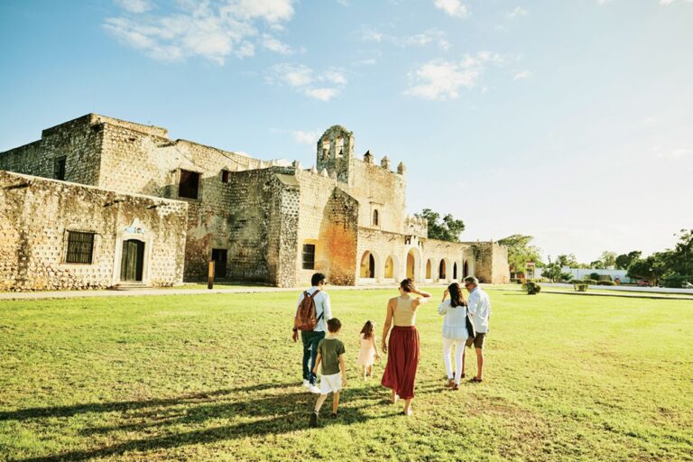 Group of people including adults and children walking on the grass toward an ancient church